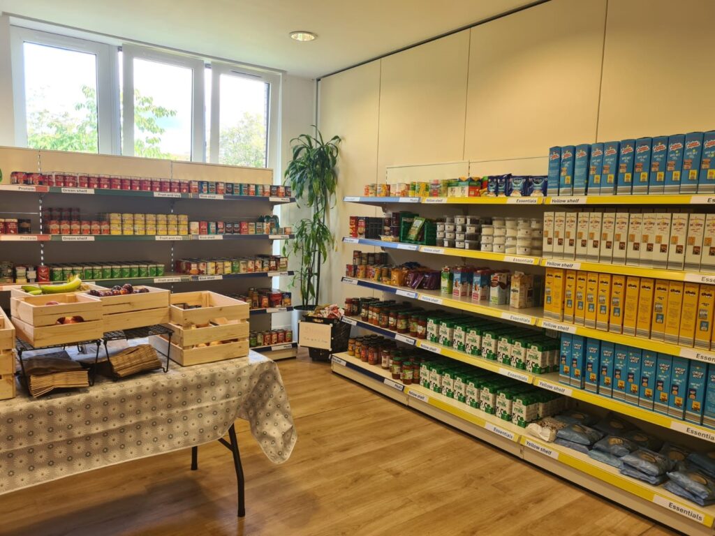 Shelves stocked with tinned food and long life milk. 